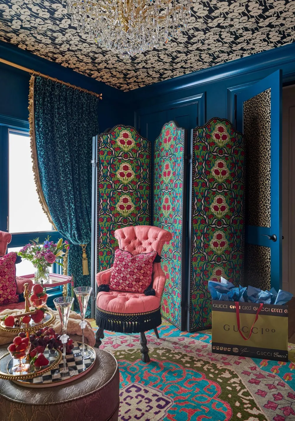 Maximalist sitting room with teal paneled walls, a pink tufted fringe armchair, floral folding screen, crystal chandelier, and Gucci bag — Lake Wylie interior design