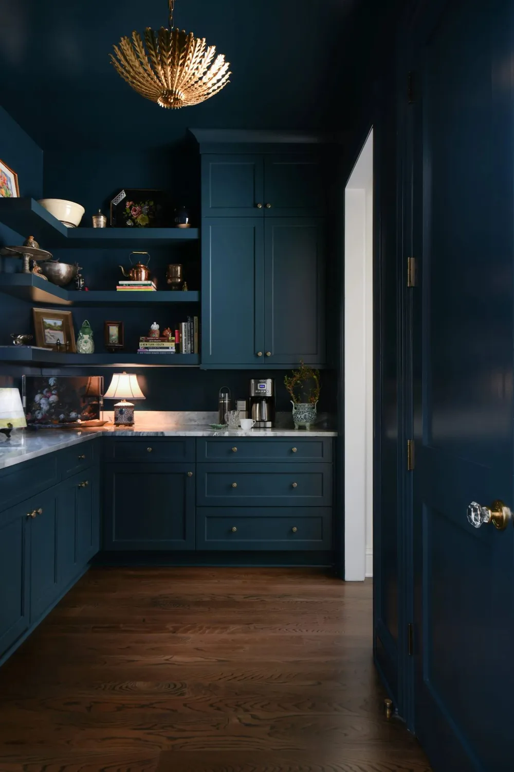 Moody navy blue butler's pantry with marble countertops, open shelving, brass chandelier, and styled vintage decor — Mount Pleasant interior design